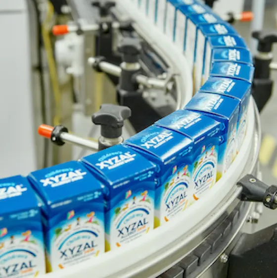 A conveyor belt carrying several packs of Children's Xyzal.